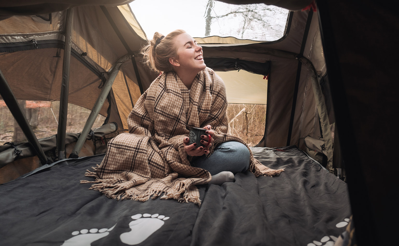 Gemütlicher Schlafplatz im Dachzelt beim Wintercamping mit Decke und warmem Ambiente