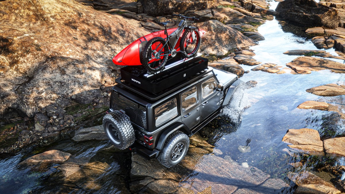 Auto mit X-Cover Dachzelt, Mountain-Bike und Kajak auf dem Dach fährt durch einen Fluss