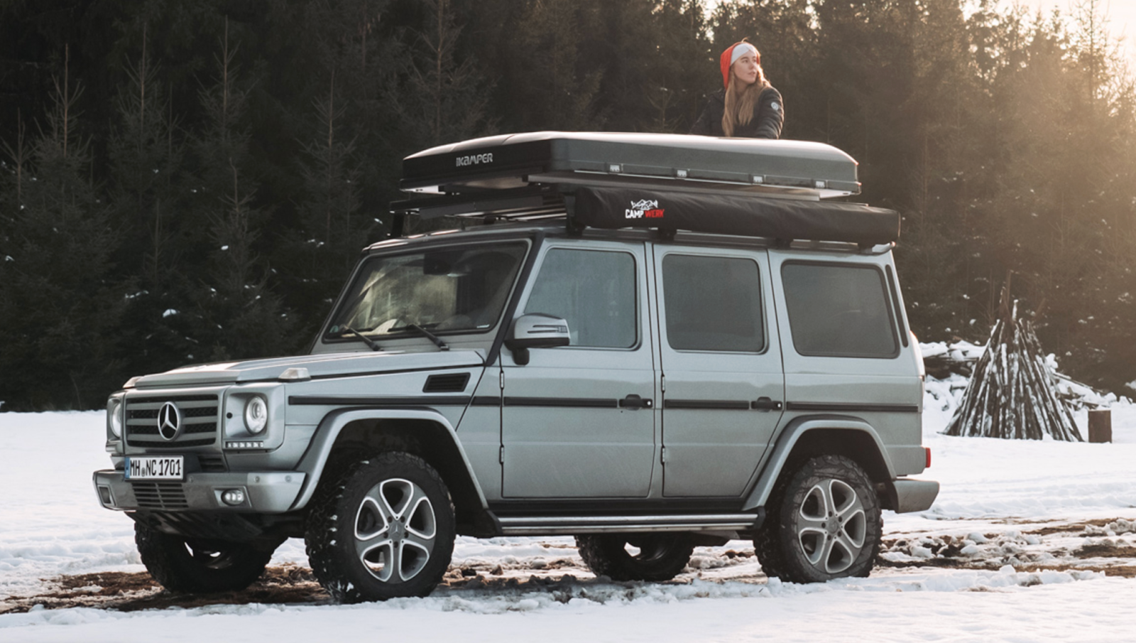 Frau mit Weihnachtsmütze sitzt auf ihrem Dachzelt