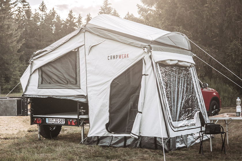 Campinganhänger mit aufgebautem Dachzelt und Vorzelt von CAMPWERK auf einem Waldstellplatz